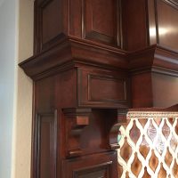 Heavy, intricate detailing on this custom cherry hood include massive moldings, accent panels and corbels. The face of the hood is hinged and opens for access and servicing of the Vent-A-Hood liner and blower system.