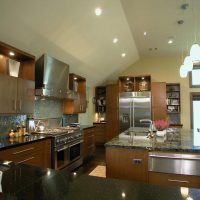 This contemporary kitchen in Friendswood features sleek yet warm wood tones, highlighted by polished granite countertops and glass backsplash tile.