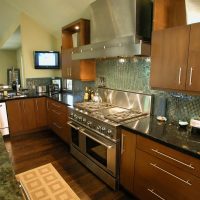 This contemporary kitchen in Friendswood features sleek yet warm wood tones, highlighted by polished granite countertops and glass backsplash tile.