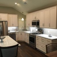 The Cambria Montgomery quartz countertops offers subtle whispers of soft blues and grays in a white background, atop white cabinets and a gray island. The corner sink cabinet is recessed for excellent ergonomics. Lots of drawers maximize storage space and accessibility.
