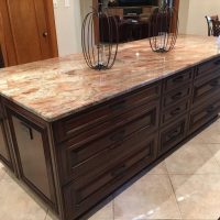 This huge custom cherry island by Wood-Mode features lots of drawers and a huge work surface of Crema Bordeaux granite