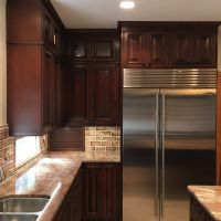 Dark cherry custom cabinetry by Wood-Mode, with glass upper doors and lighted interiors. Built-in SS refrigerator.