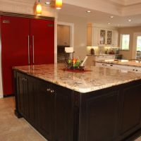 Traditional white kitchen has a dark cherry island, with bright red appliances & accents & carved accents. Two islands and a double tray ceiling anchor the center of this chef's kitchen. Storage of these frameless cabinets is maximized with lots of drawers and upper cabinet storage. Bright red Viking side-by-side freezer & refrigerators.