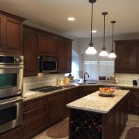Light gray walls provide a dramatic backdrop for the dark stained cabinets. LED lighting provides better light without adding unnecessary heat in the kitchen. The beautiful tile & stone backsplashes are uninterrupted by electrical outlets (custom power strips are concealed below the upper cabinets).