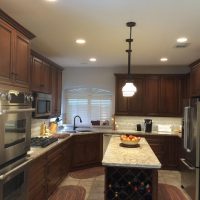 Light gray walls, countertops and backsplashes provide a dramatic backdrop for the dark stained cabinets. LED lighting provides better light without adding unnecessary heat in the kitchen. The beautiful tile & stone backsplashes are uninterrupted by electrical outlets (custom power strips are concealed below the upper cabinets).