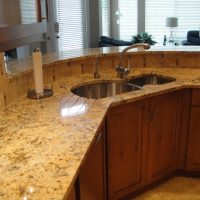 Grooves in the granite countertop sloping into the sink provide dish drainage space on the countertop leaving both sink bowls