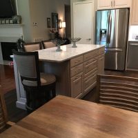 The Cambria Montgomery quartz countertops offers subtle whispers of soft blues and grays in a white background, atop a gray stained island. Abundant drawer storage space and island seating.