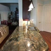 We removed this major wall that used to divide the kitchen from the Family Room, providing our clients with an amazing open concept kitchen, as well as additional seating at the counter. Note that there are no unsightly outlets or switches in these beautiful backsplashes; all the outlets are cleverly concealed below the upper cabinets. Gorgeous Fusion quartzite countertops add excitement to the dramatic dark cherry cabinets.