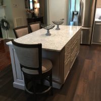The Cambria Montgomery quartz countertops offers subtle whispers of soft blues and grays in a white background, atop a gray stained island. Abundant drawer storage space and island seating.