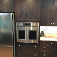Refrigerator niche (partial view) and custom tall oven cabinet with a dark stain on maple, and a French door convection oven.