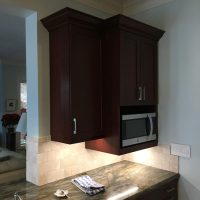 Note that there are no unsightly outlets or switches in these beautiful backsplashes; all the outlets are cleverly concealed below the upper cabinets. Gorgeous Fusion quartzite countertops add excitement to the dramatic dark cherry cabinets