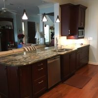 We removed this major wall that used to divide the kitchen from the Family Room, providing our clients with an amazing open concept kitchen, as well as additional seating at the counter. Note that there are no unsightly outlets or switches in these beautiful backsplashes; all the outlets are cleverly concealed below the upper cabinets. Gorgeous Fusion quartzite countertops add excitement to the dramatic dark cherry cabinets.