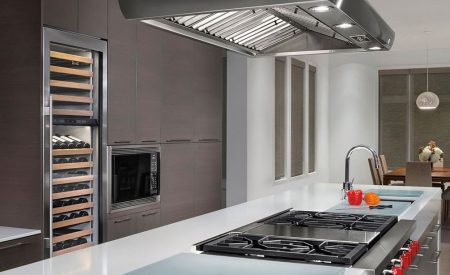 Modern kitchen with tall integrated wine fridge and sleek island cooktop.